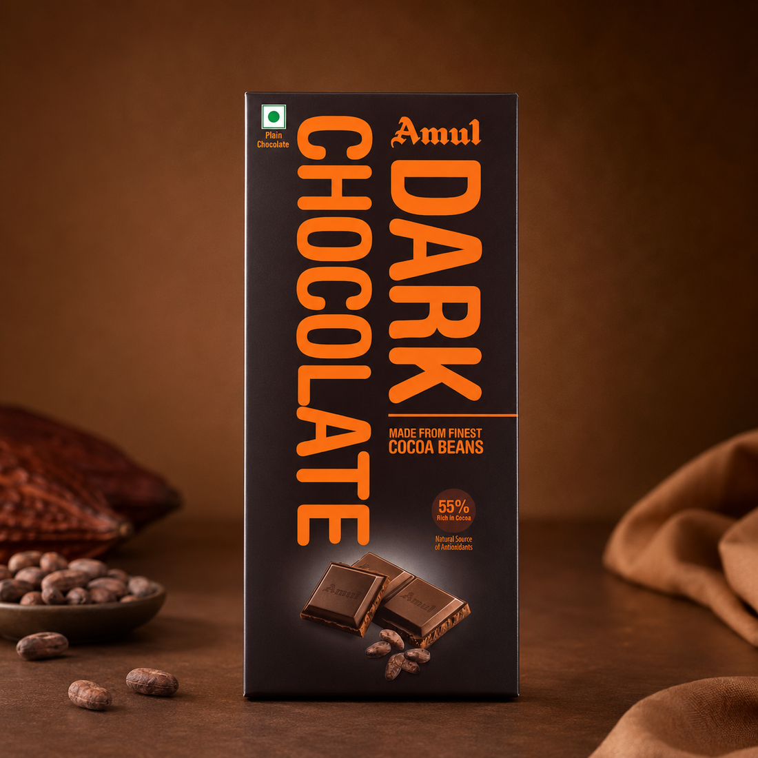 Premium Amul Dark Chocolate packaging displayed upright on a warm brown professional studio background with cocoa beans and soft fabric accents.