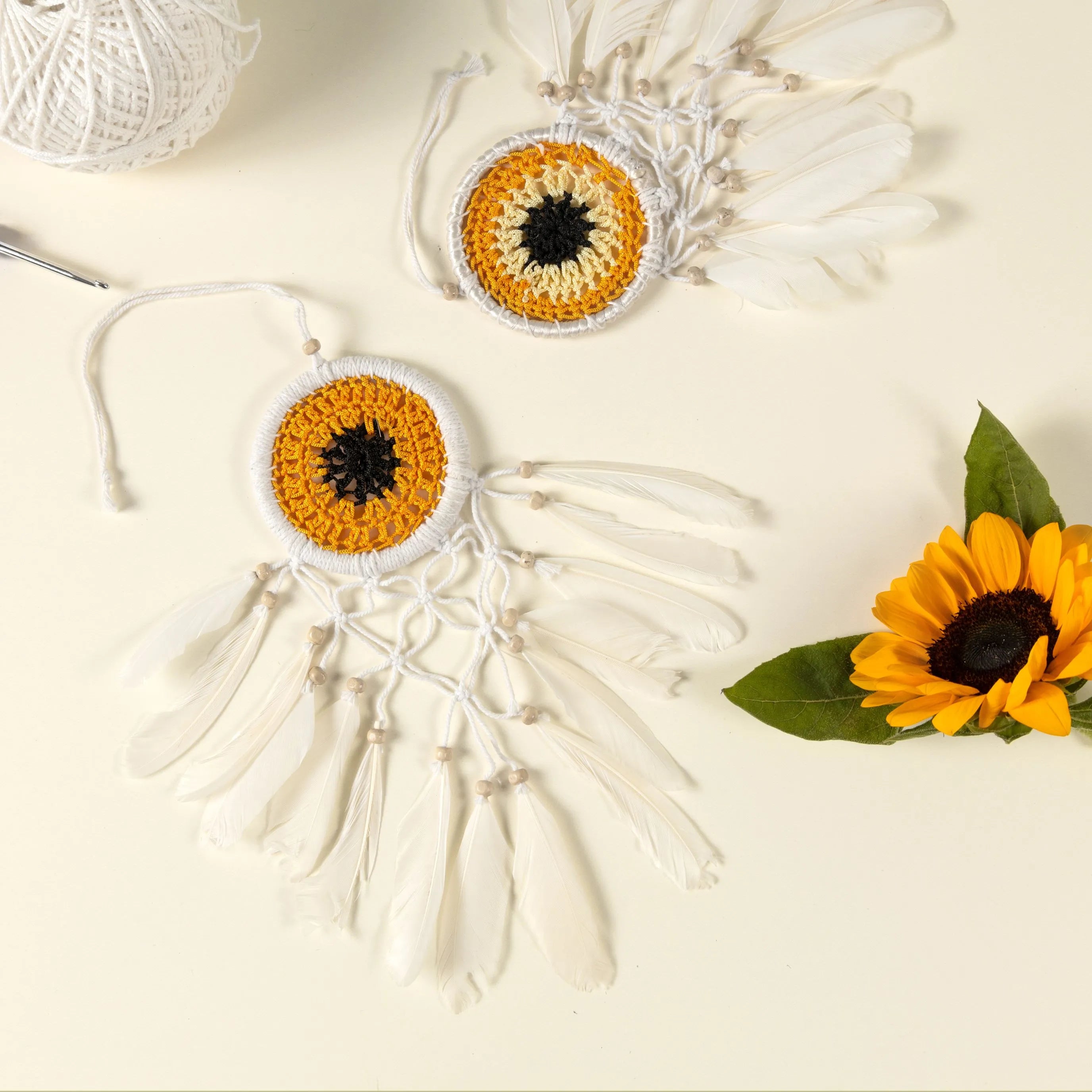 Handmade yellow and white sunflower-inspired dreamcatcher with feathers and macramé detailing