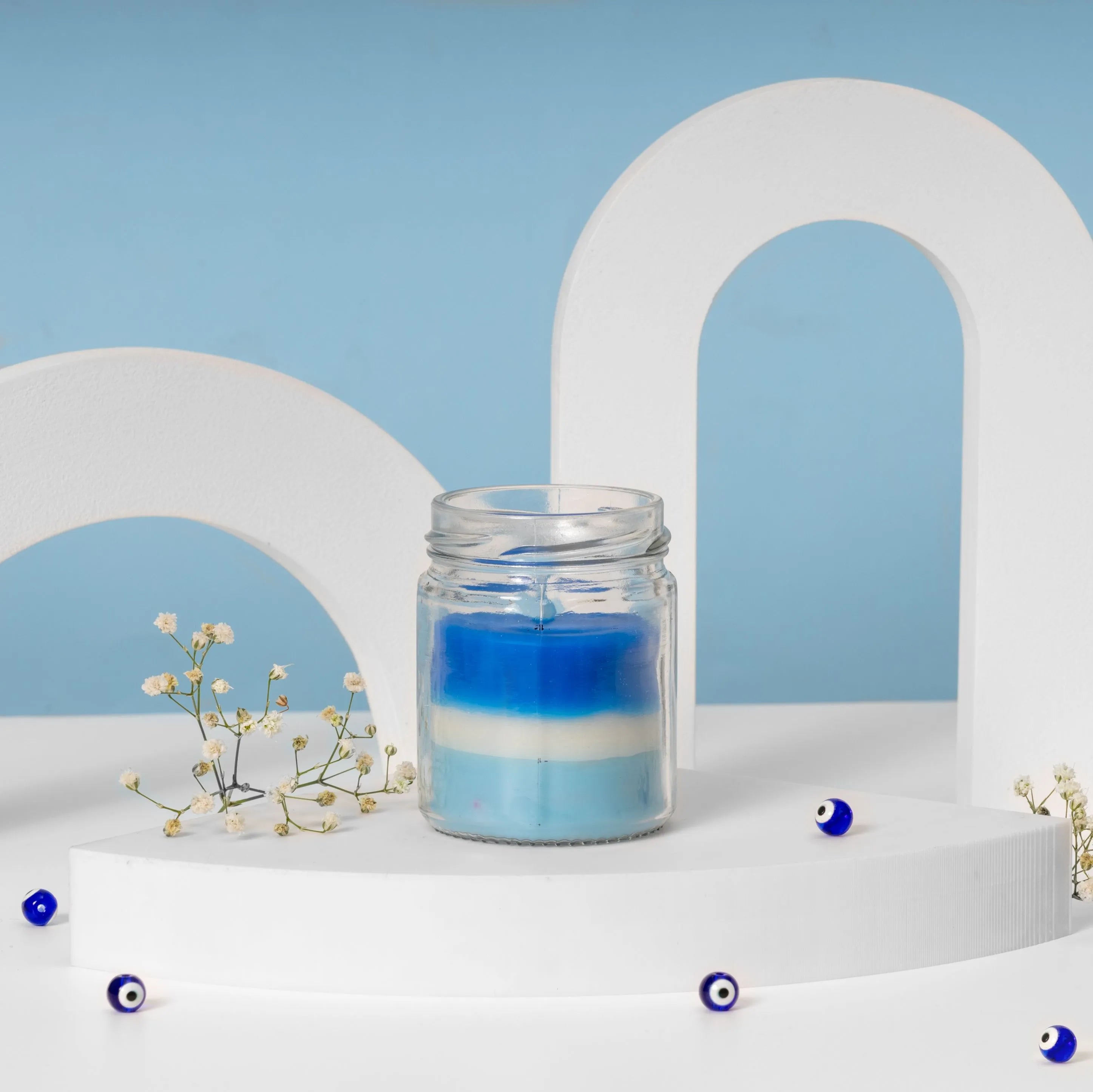 Blue and white scented candle in a glass jar, beautifully styled as part of an Evil Eye themed gift hamper with a calming and elegant design.