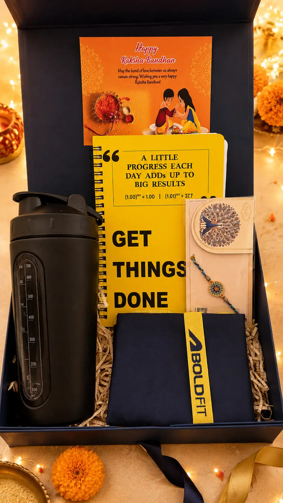 Raksha Bandhan fitness gift hamper for brother with protein shaker, motivational daily planner, Rakhi, festive greeting card, and BOLDFIT accessory, beautifully arranged in a premium navy gift box.