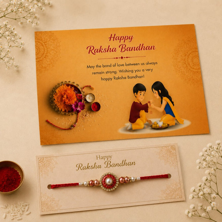 A Raksha Bandhan greeting card and matching wristband displayed on a cream surface with decorative flowers and a small bowl of red powder. The card is orange with 'Happy Raksha Bandhan' text and an illustration of a boy and girl.