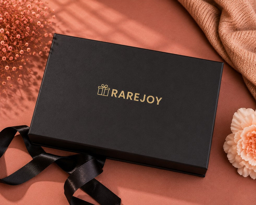 A black rectangular RareJoy gift box with gold foil lettering.