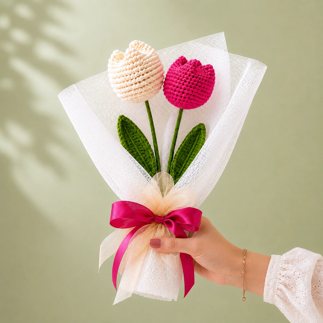 Handcrafted crochet tulip bouquet featuring one white and one vibrant pink tulip with green leaves, wrapped in elegant white mesh and finished with a pink satin ribbon bow